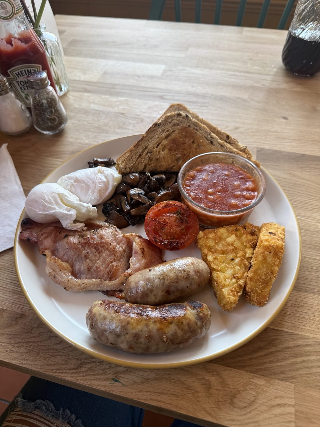 Breakfast plate with poached eggs, bacon, sausages and hash browns